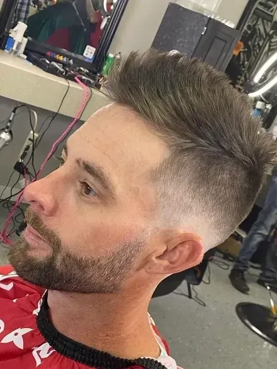 A man with a beard is getting his hair cut at a barber shop.