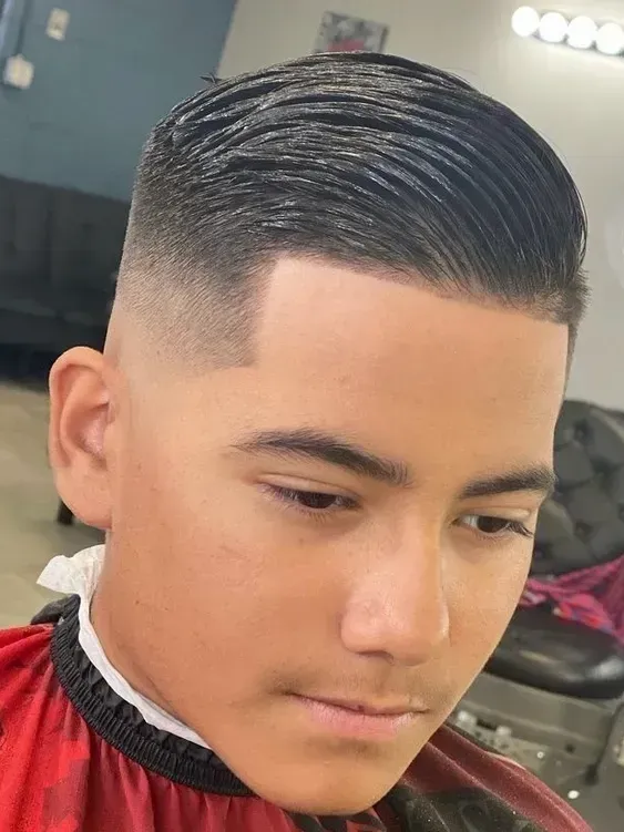 A young boy is getting his hair cut at a barber shop.
