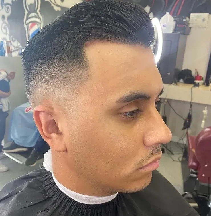 A man is getting his hair cut at a barber shop.