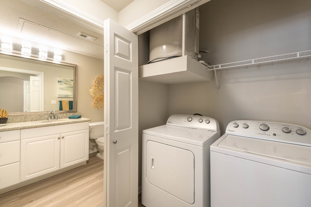 Laundry closet with a washer and dryer beside a bathroom vanity.