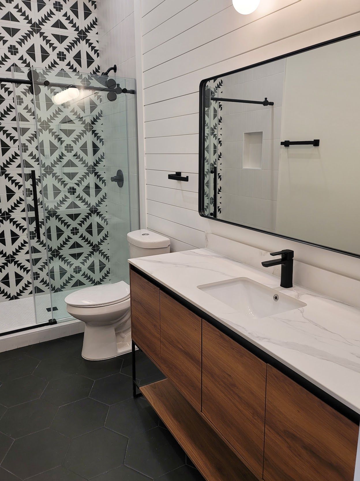 A bathroom with a toilet , sink , mirror and shower.