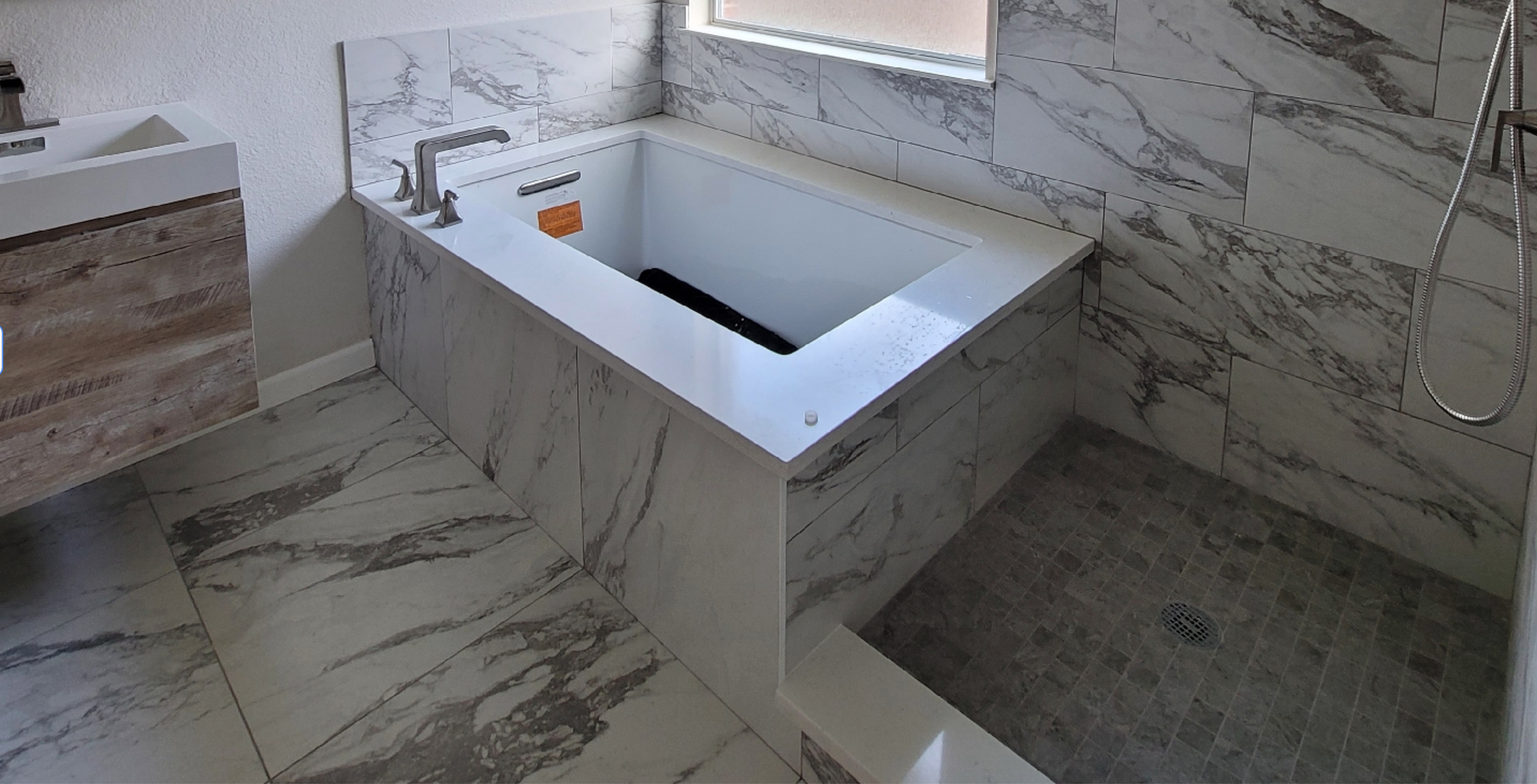 A bathroom with a bathtub , sink , and shower.