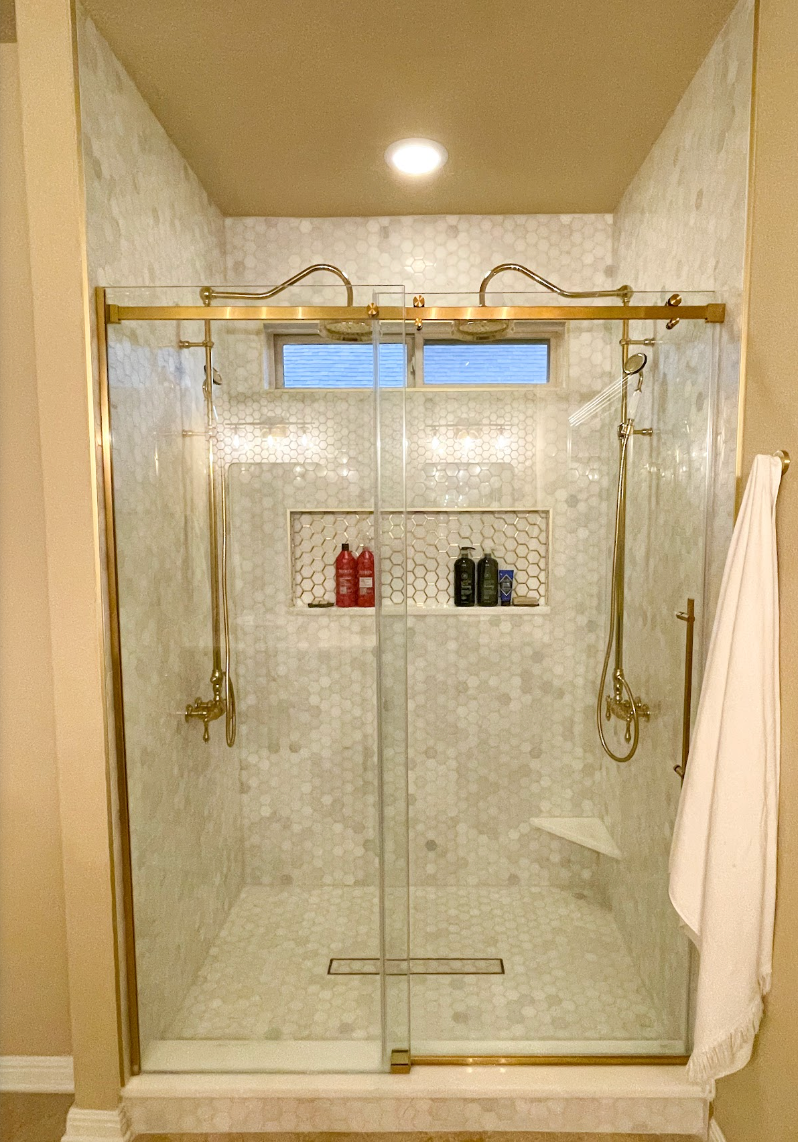 A bathroom with a walk in shower with a sliding glass door.