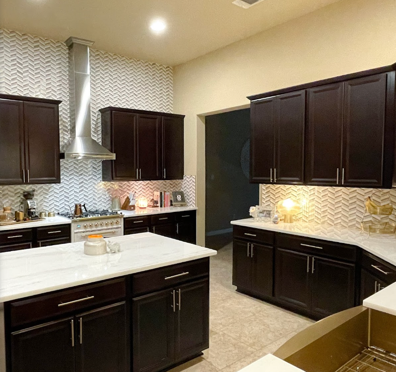A kitchen with dark cabinets and white counter tops
