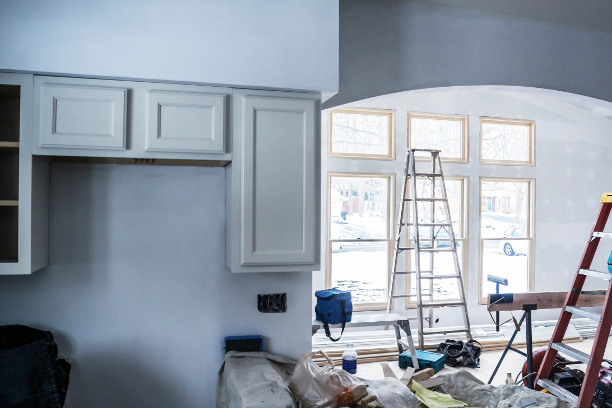 A kitchen is being remodeled with white cabinets and a ladder.