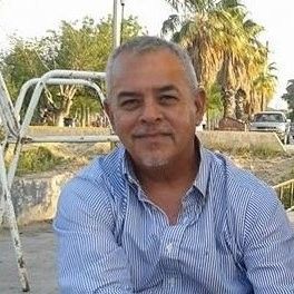A man in a blue and white striped shirt is sitting in a chair.