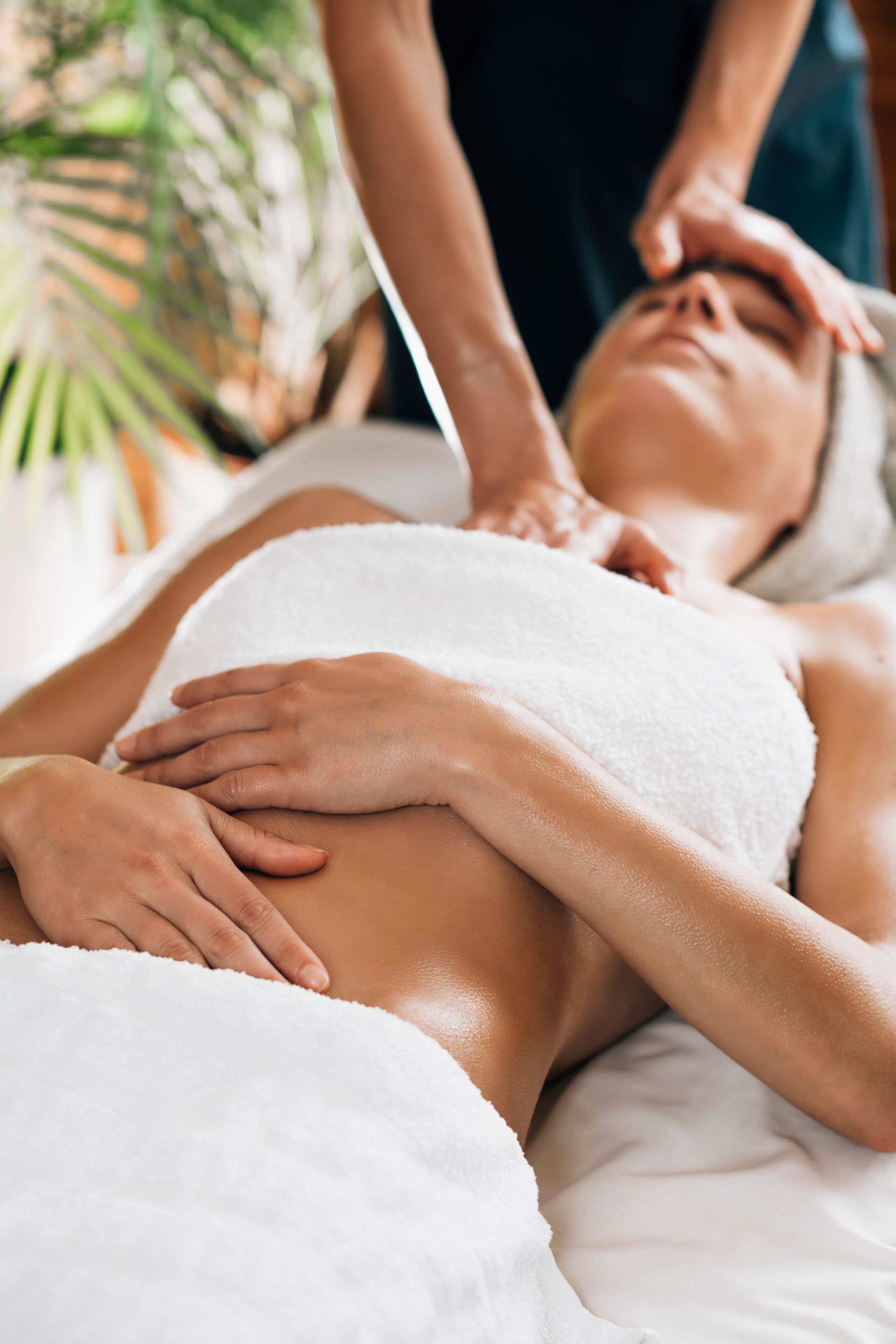 A woman wrapped in a towel is getting a massage at a spa.