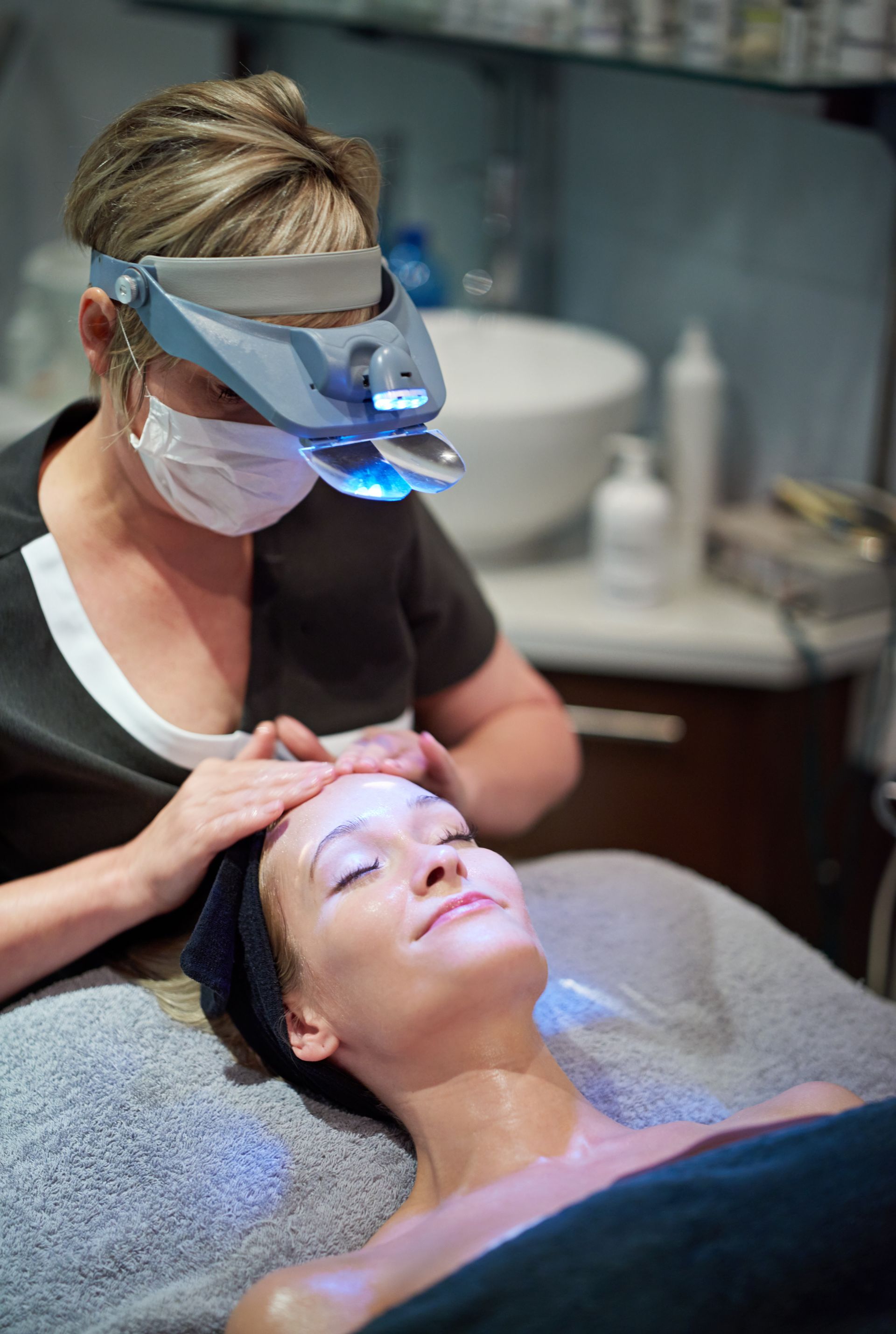 A woman wearing a mask is getting a treatment on her face