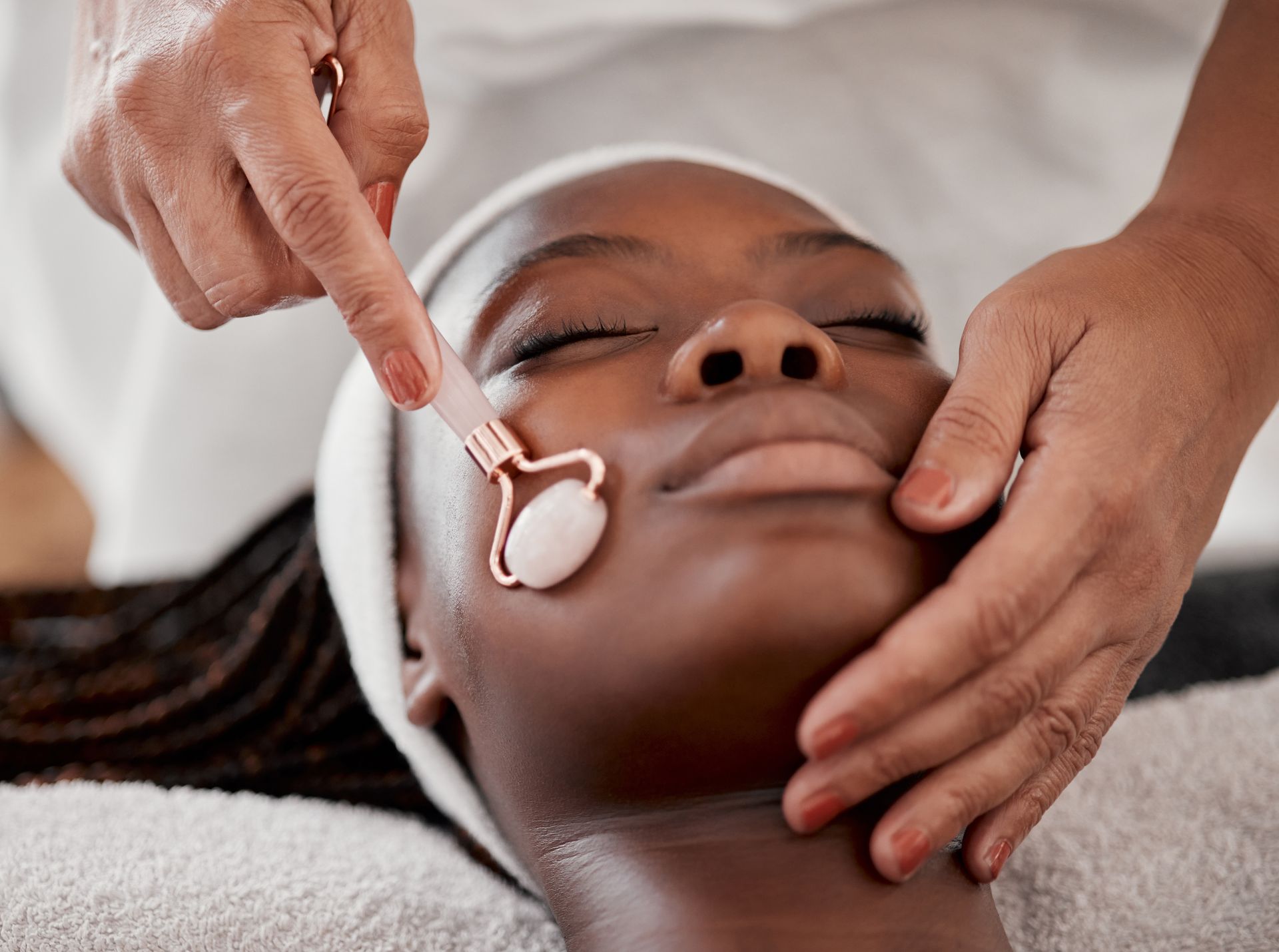 A woman is getting a facial massage with a roller on her face.