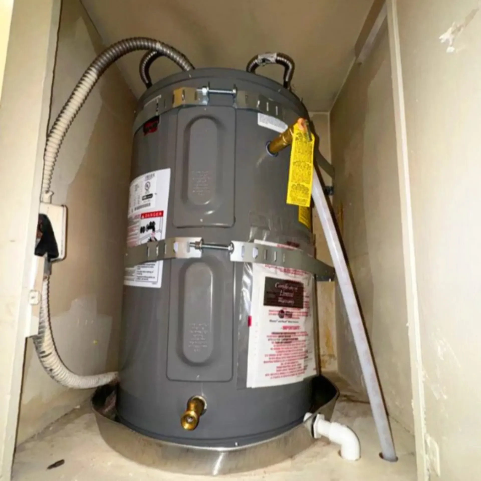 GTZ Plumbing Service LLC - A water heater is sitting in a cabinet with a hose attached to it