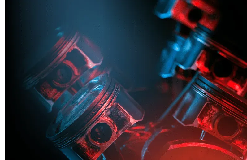 Engine pistons, illuminated with red and blue light.