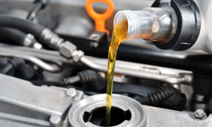 Pouring oil into a car engine; clear oil flowing from a bottle.