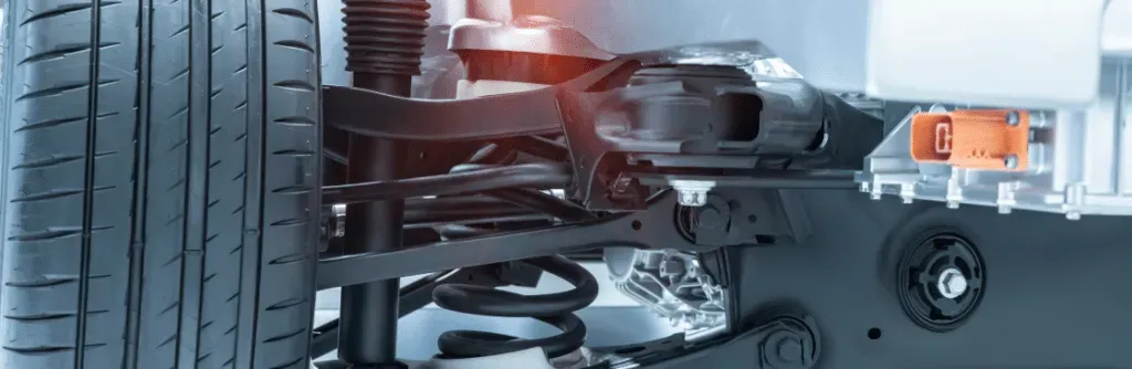 Close-up of a car suspension system with tire, shocks, and related components.