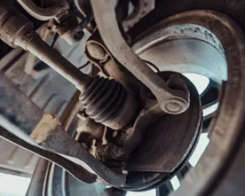Underneath view of a car's suspension system, including wheel, axle, and control arms.