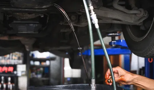 Oil draining from a car during an oil change in a garage.