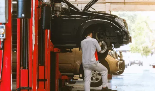 Mechanic working on a car raised on a lift in a garage.