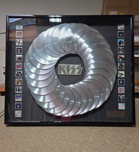 Framed Kiss album display with silver records in a circular pattern and album covers.