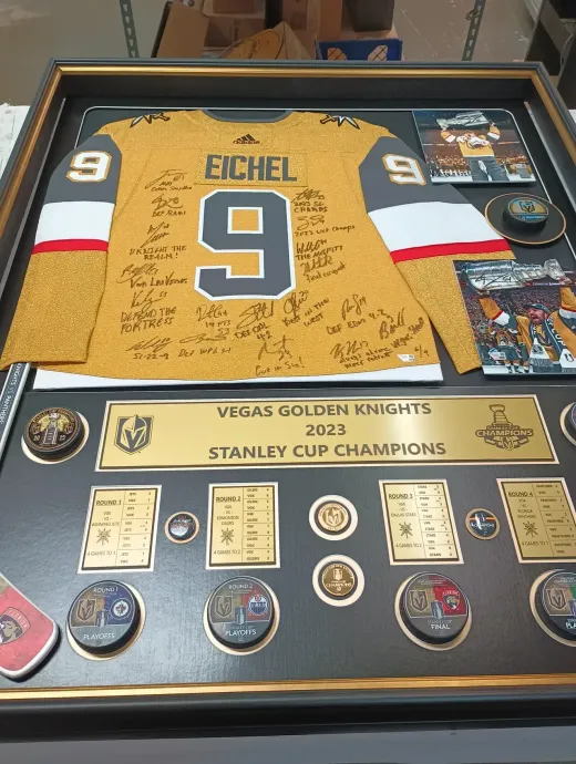 Framed Vegas Golden Knights Stanley Cup Champions jersey with autographs and memorabilia. Gold, black, and grey colors.