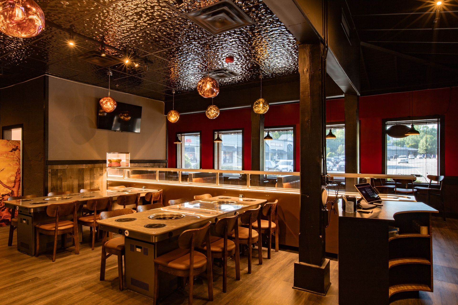 Interior of a restaurant with tables, chairs, and hanging lights. Red and black walls and a decorative ceiling.