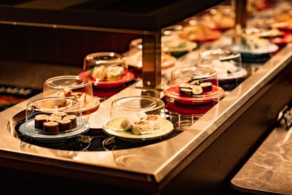 A conveyor belt filled with plates of food in a restaurant.