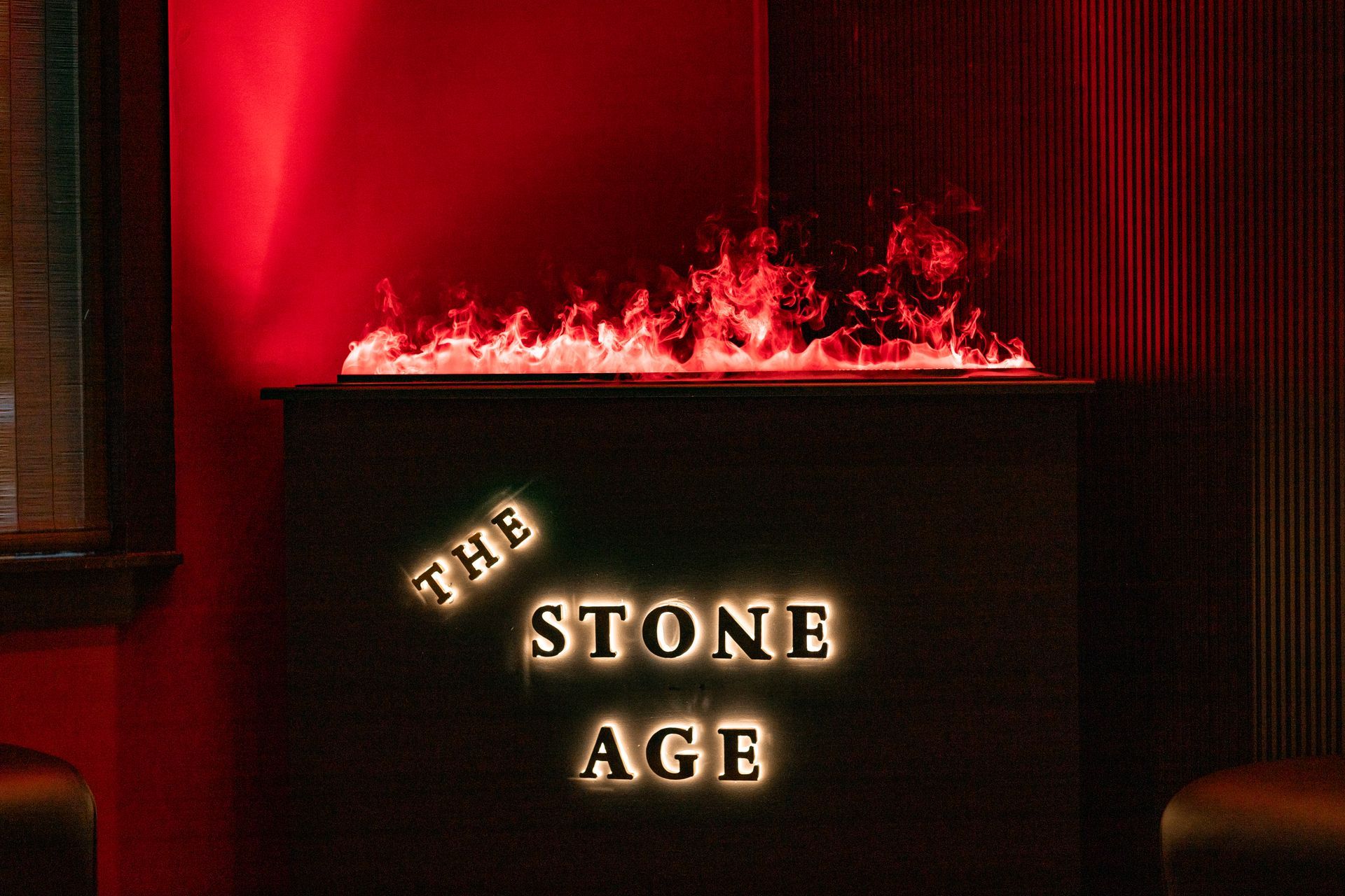 A fireplace with flickering red flames above a dark sign that reads 