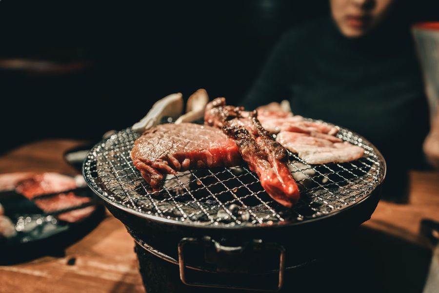A person is sitting at a table eating meat on a grill.