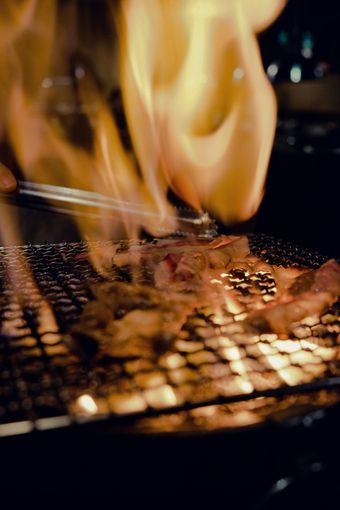 A close up of a grill with flames coming out of it.