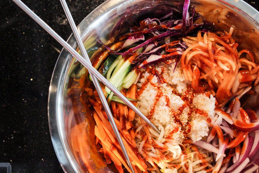 Bowl of Bibimbap with colorful vegetables and chopsticks.