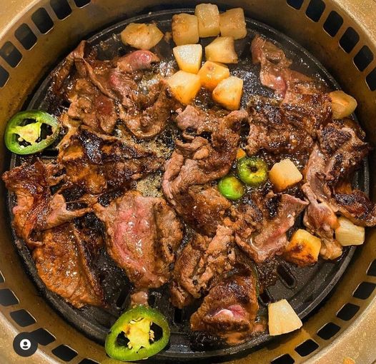 A close up of a plate of meat and vegetables on a grill.