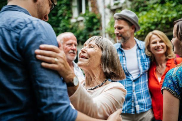 A group of people are standing around a man and woman hugging each other.