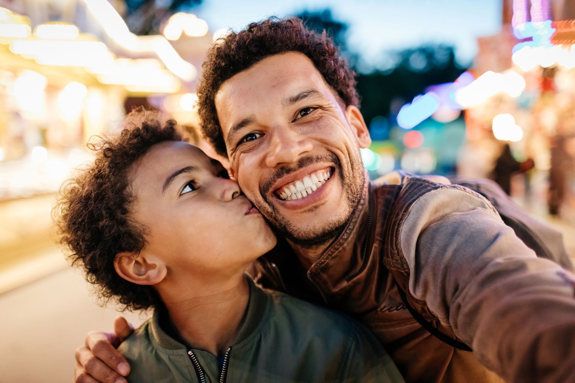 A man and a boy are taking a selfie at a carnival.