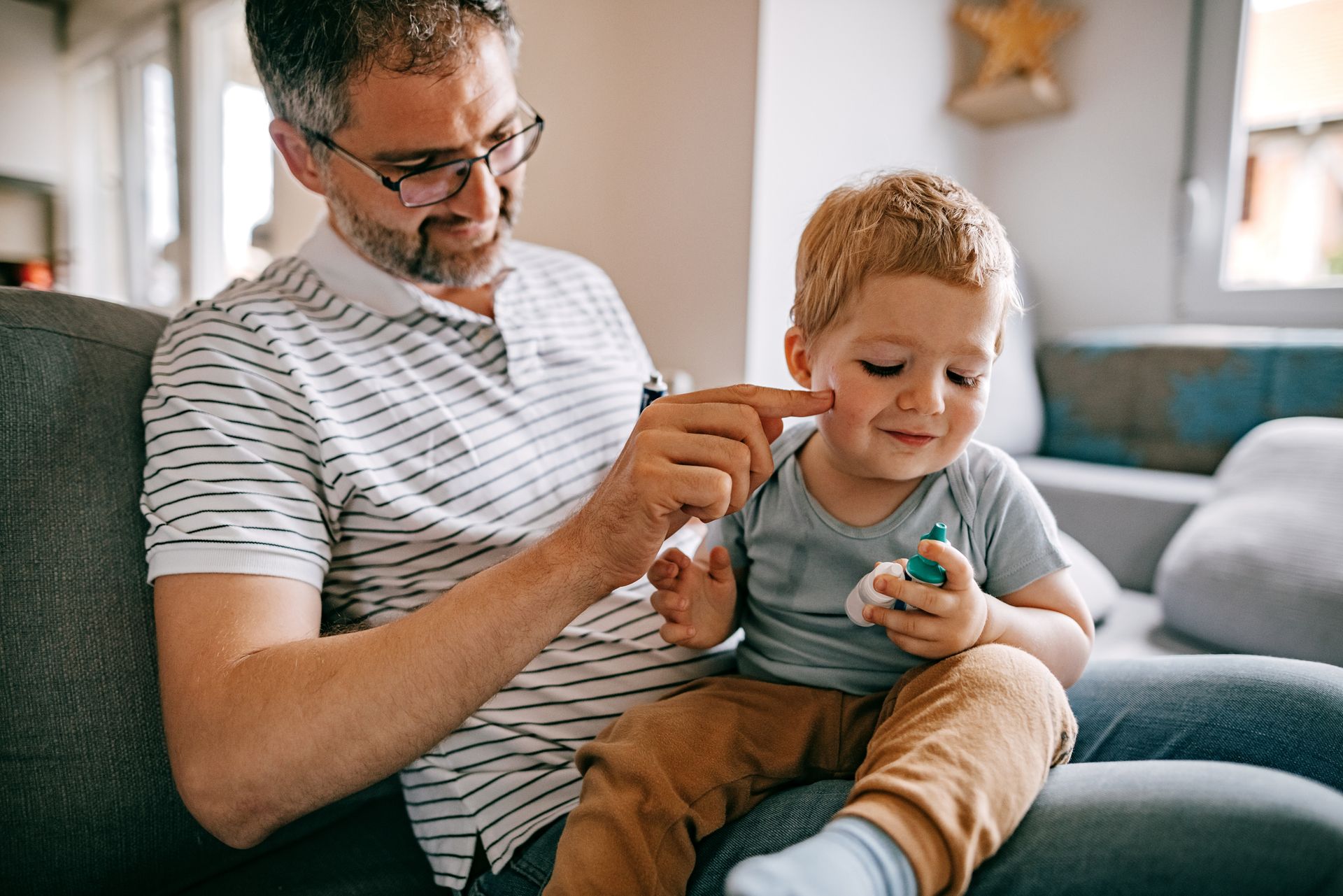 A man and a little boy are sitting on a couch playing with a toy.
