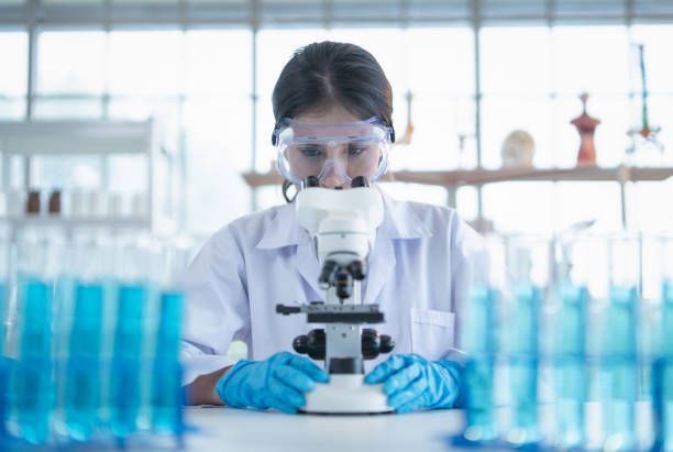 A female scientist is looking through a microscope in a laboratory.