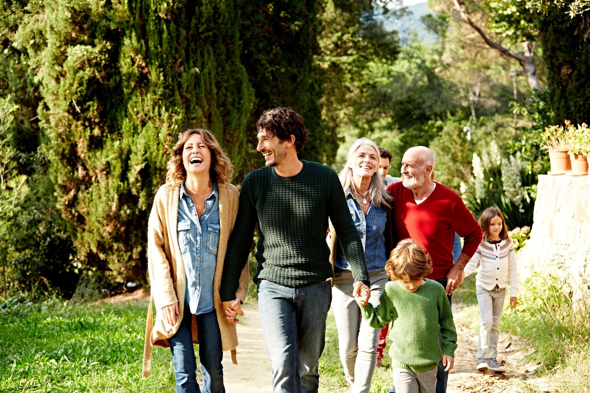 A family is walking down a path holding hands.