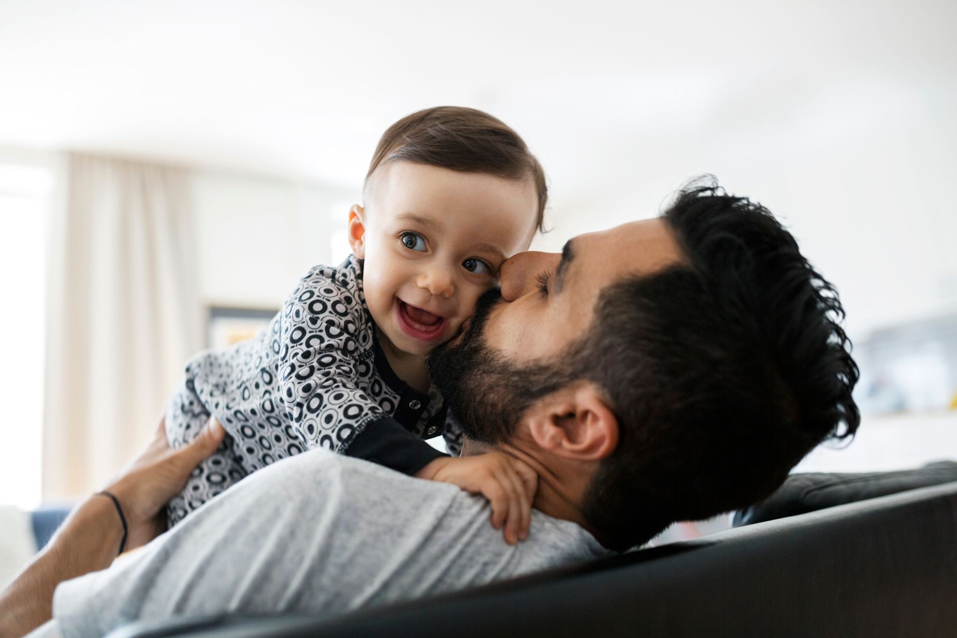 A man is holding a baby in his arms and kissing it on the cheek.