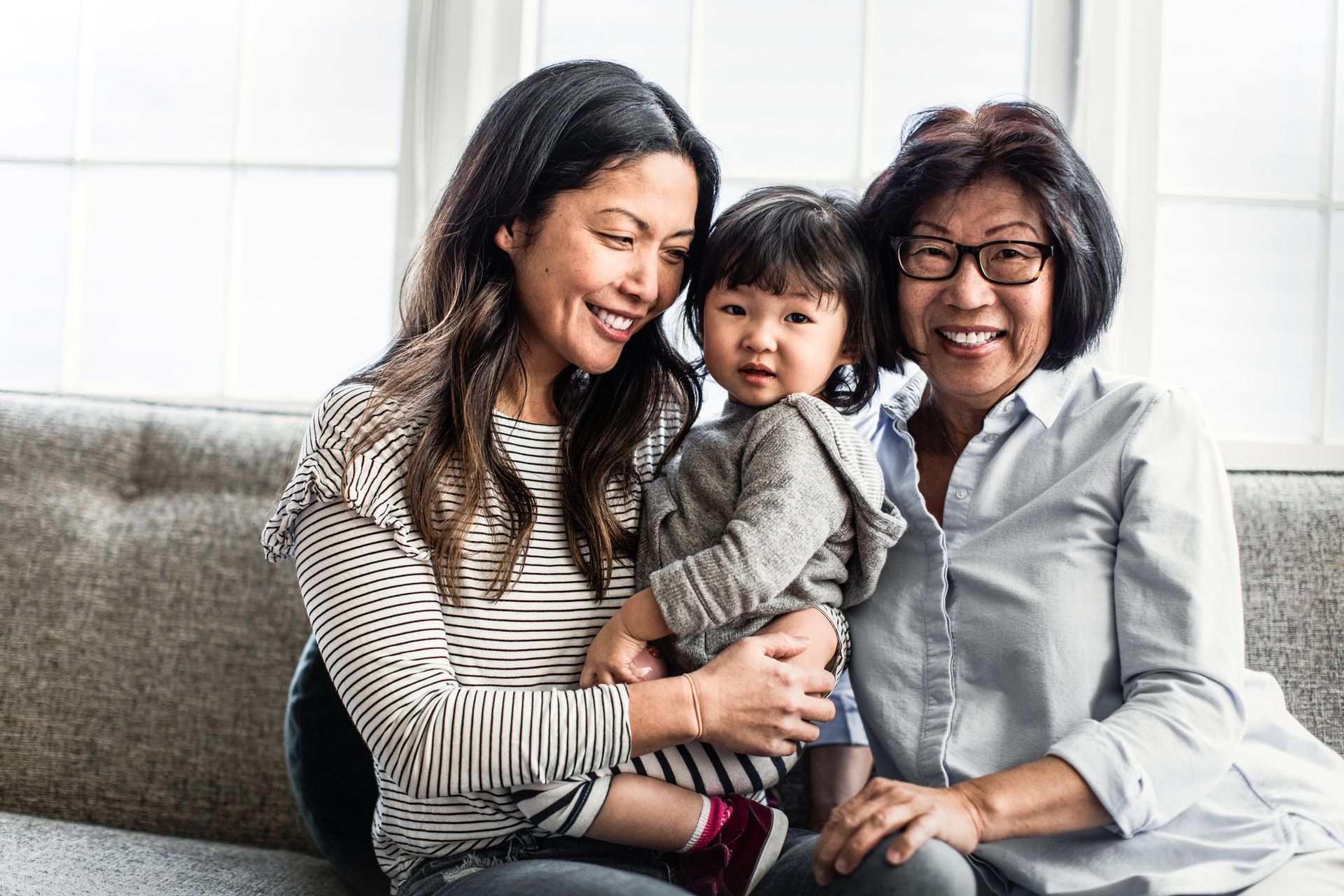 A woman is holding a baby while sitting on a couch with two other women.
