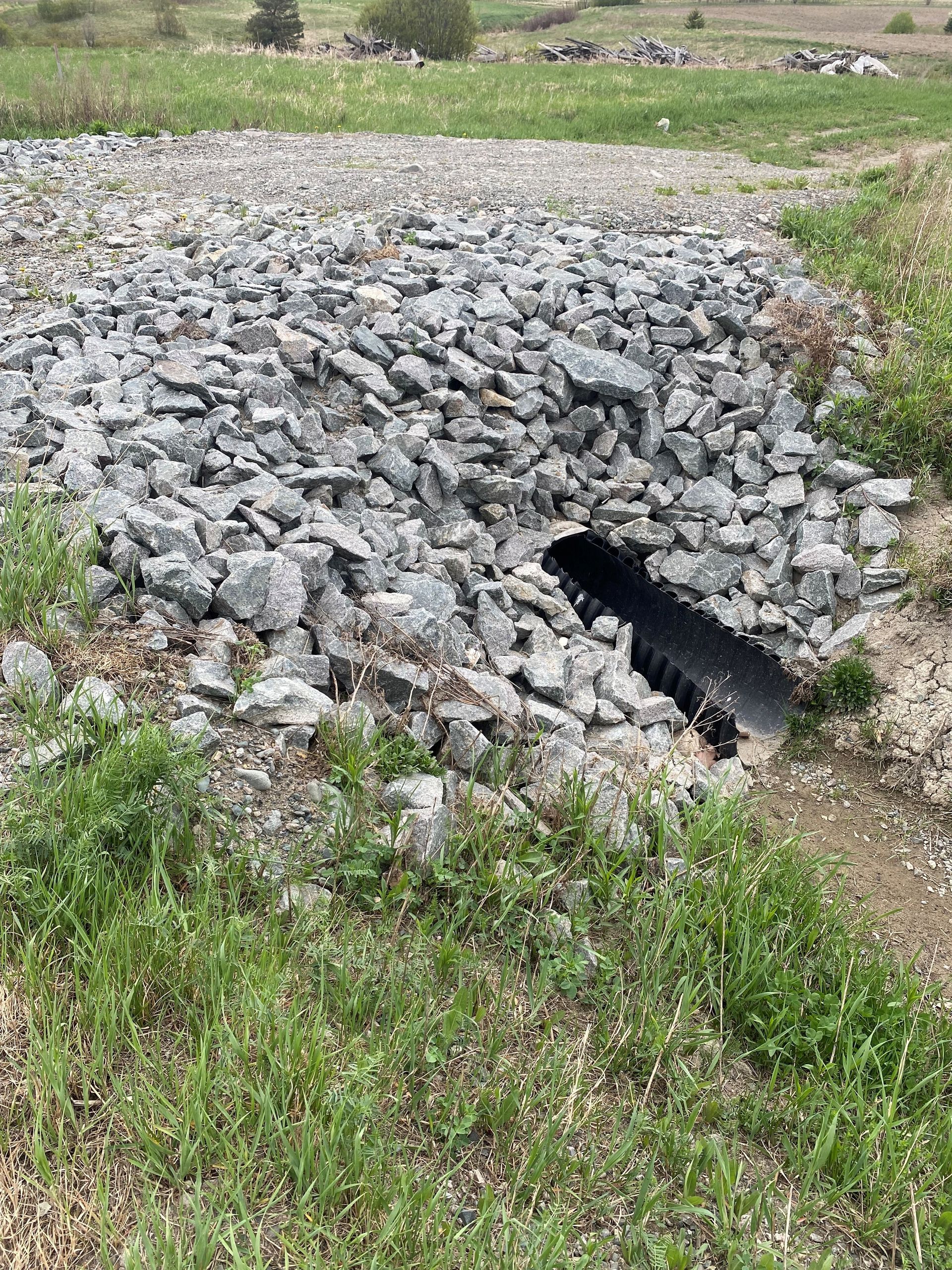 Un gros tas de pierres et un tuyau au milieu d un champ.