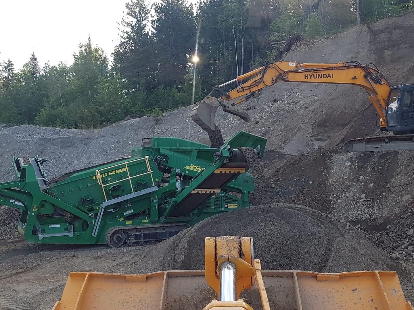 Une excavatrice Hyundai creuse un tas de terre.