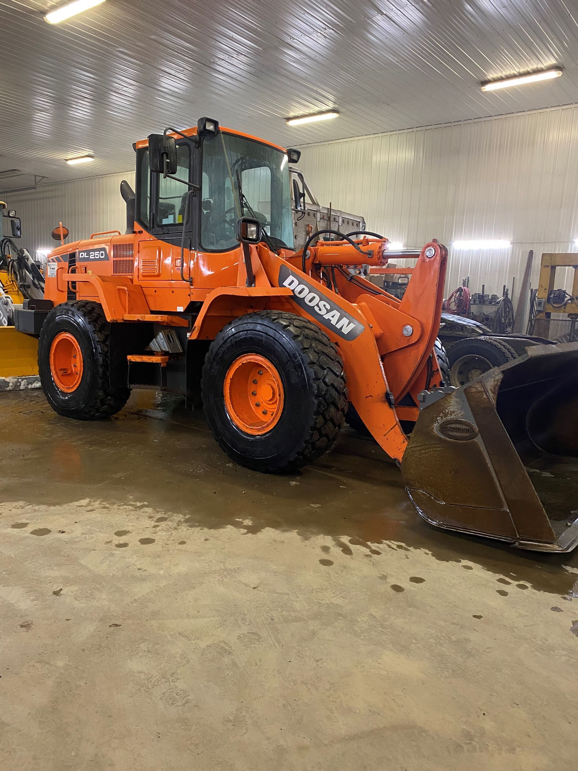 Une grande chargeuse sur pneus orange est garée dans un garage.