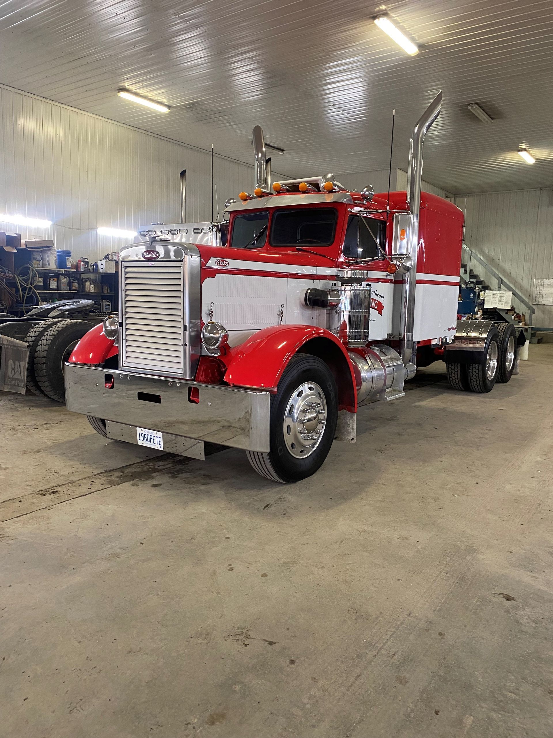 Un semi-remorque rouge et blanc est garé dans un garage.