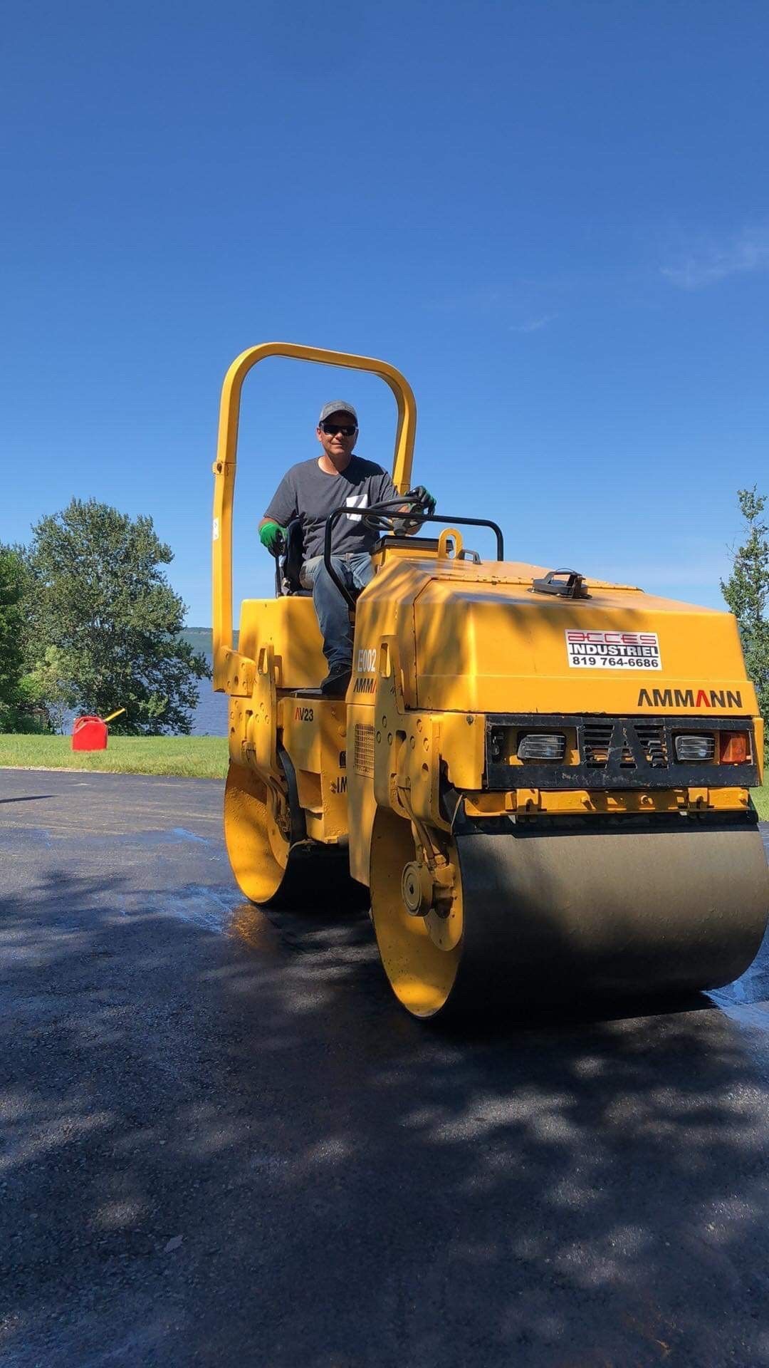 Un homme conduit un rouleau jaune sur une route.