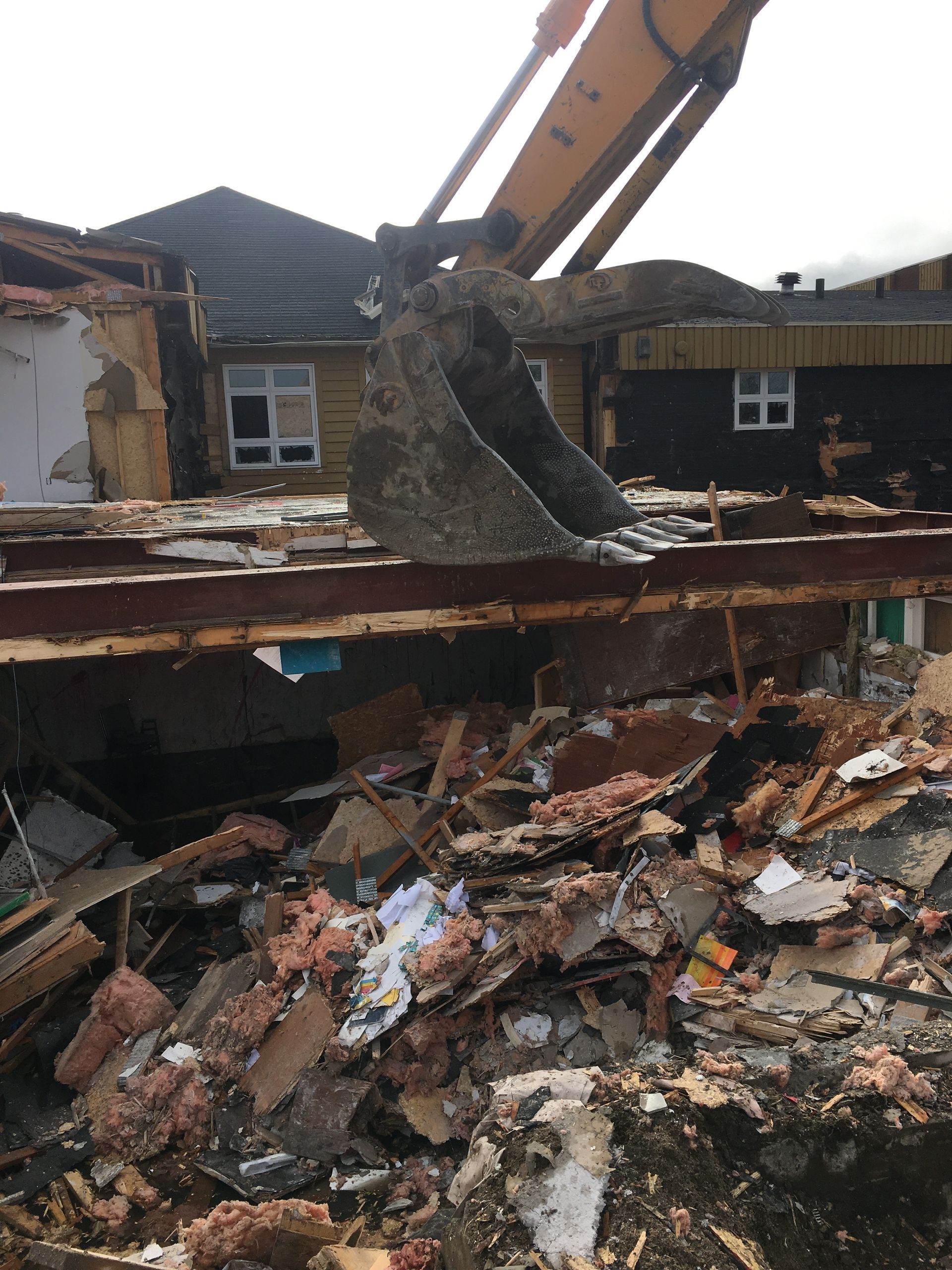 Un bulldozer démolit une maison avec beaucoup de décombres.