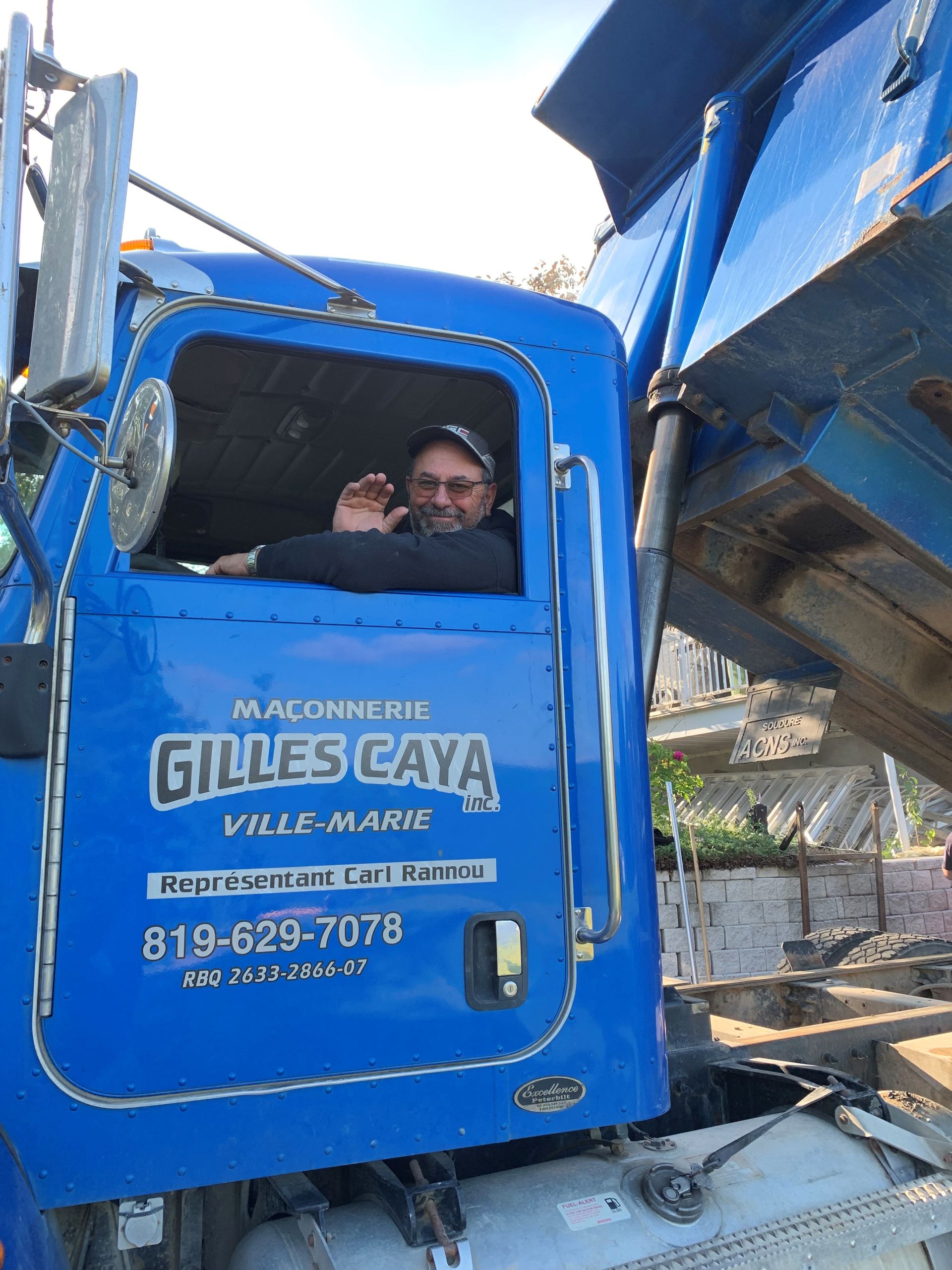 Un homme est assis sur le siège conducteur d un camion-benne bleu.