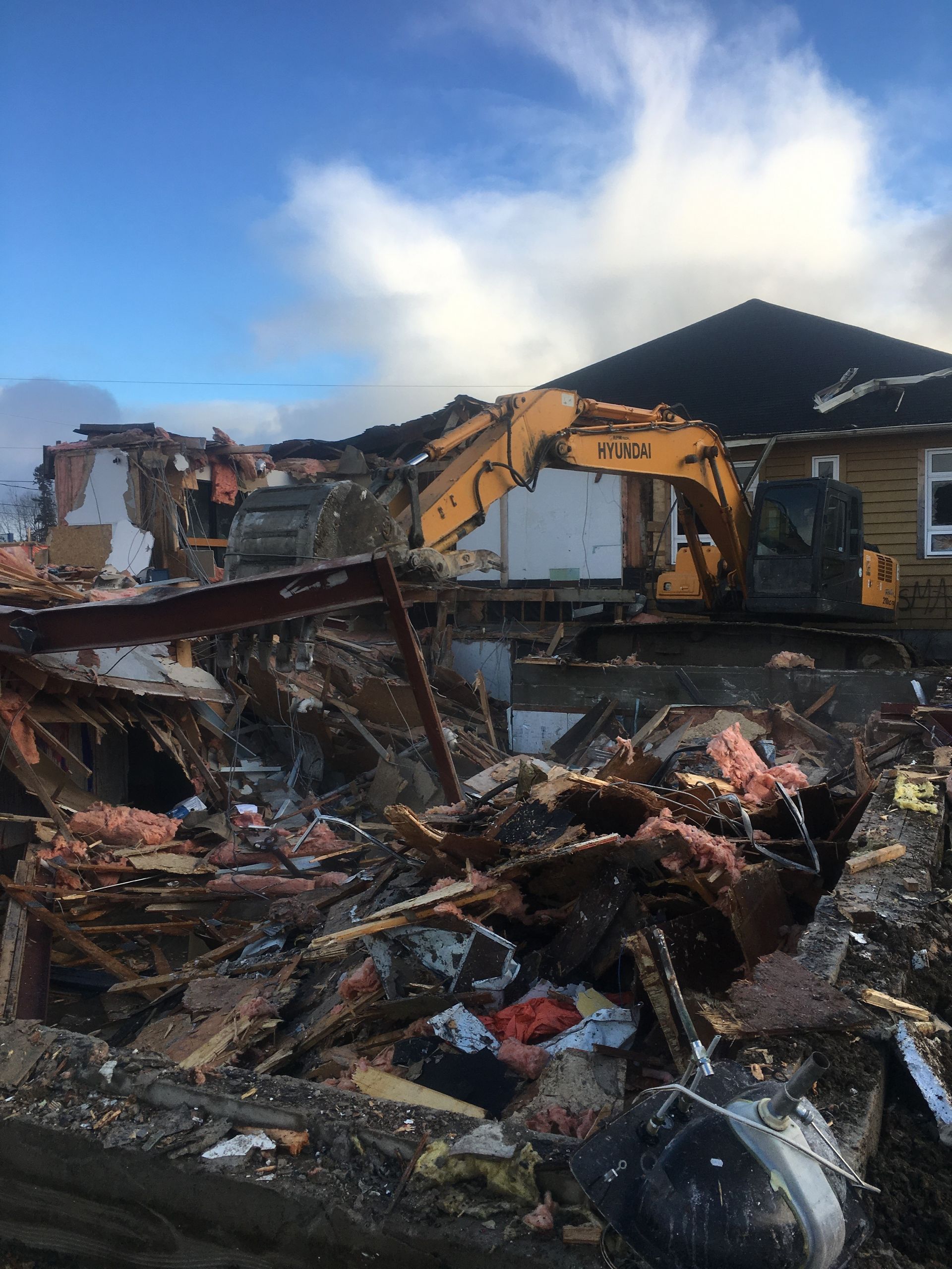 Une grande excavatrice jaune démolit une maison.