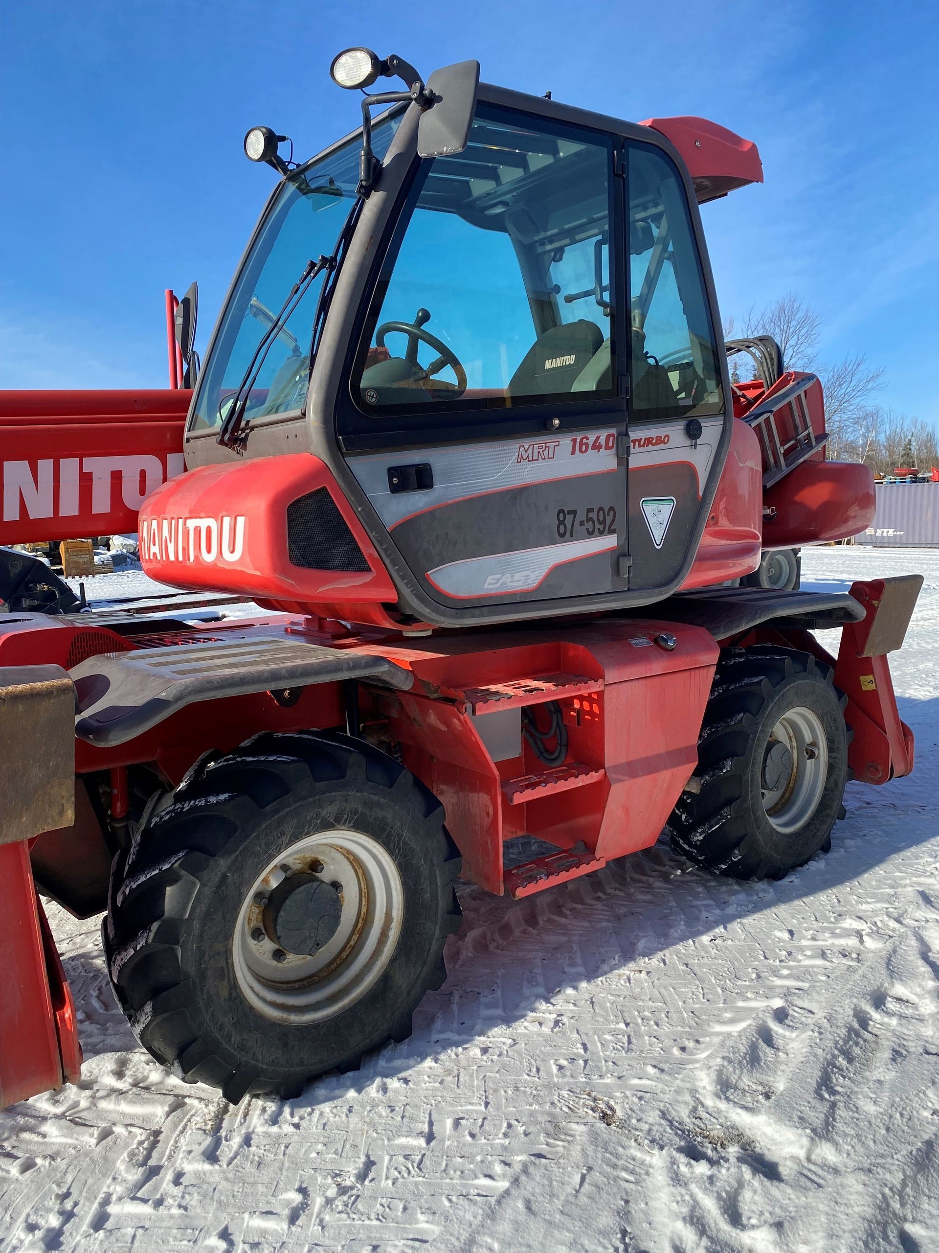 Un chariot élévateur rouge est garé dans la neige.