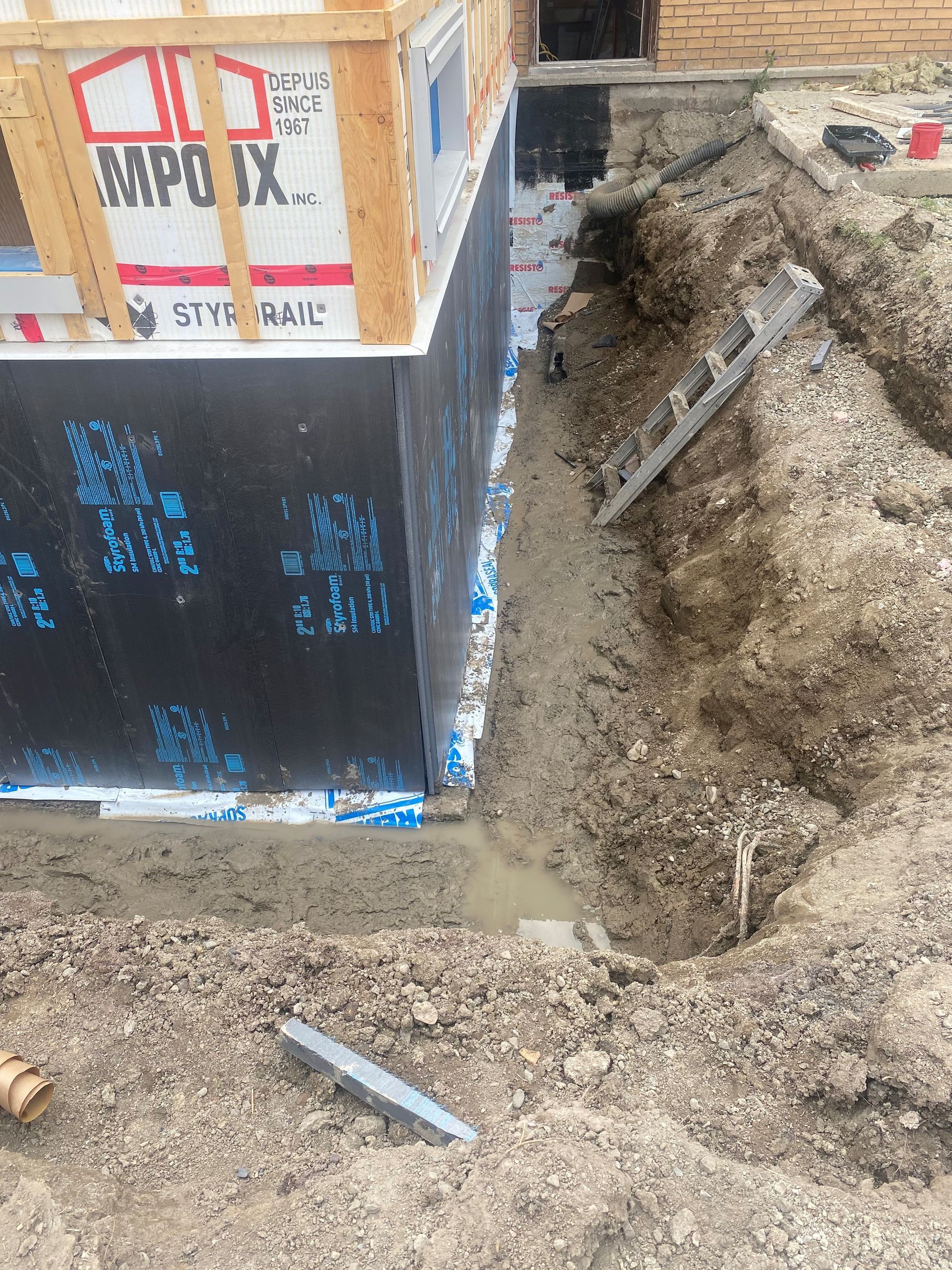 Un grand trou dans le sol à côté d une maison en construction.
