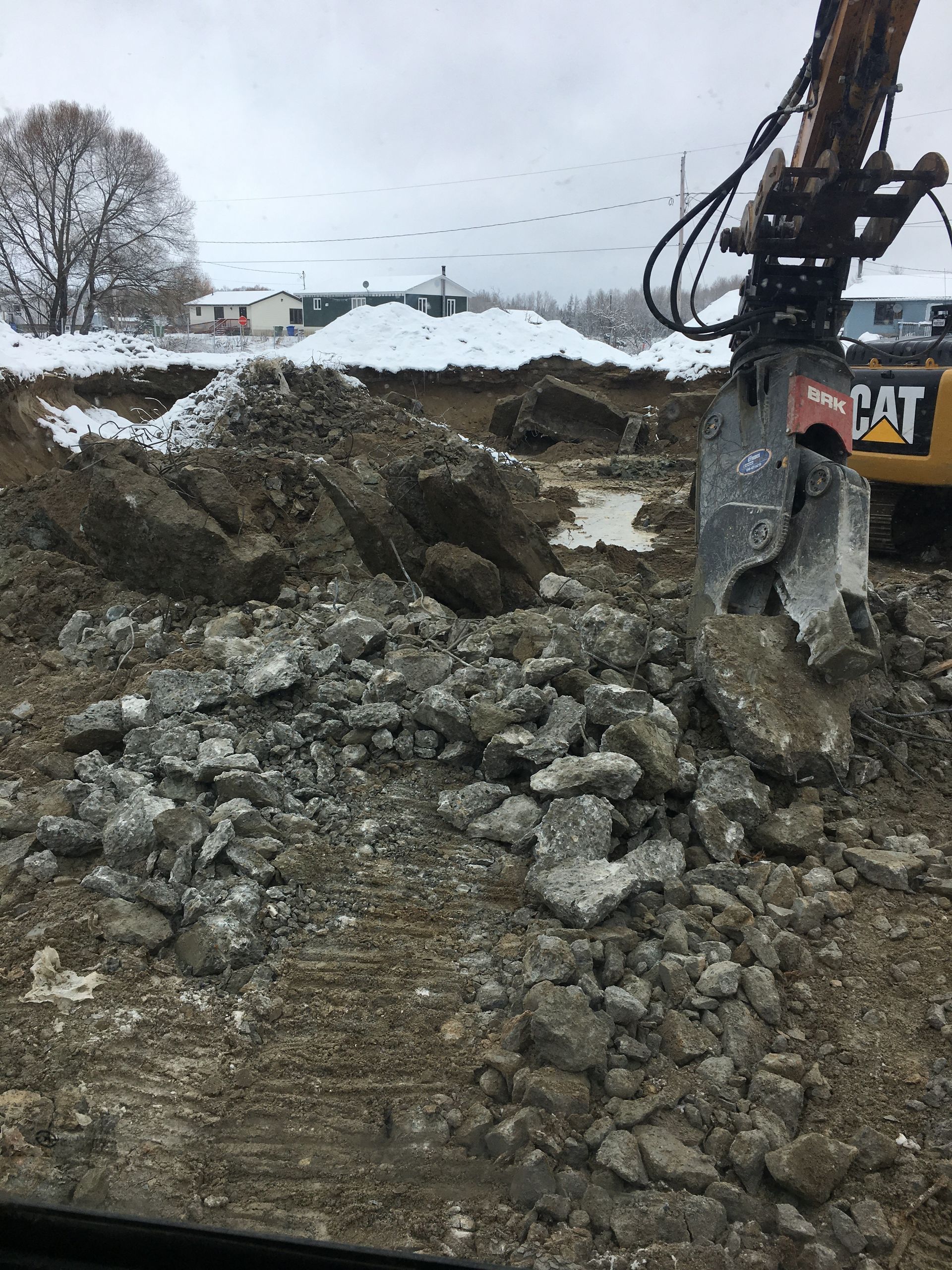 Un gros tas de roches est déplacé par une excavatrice à chat.