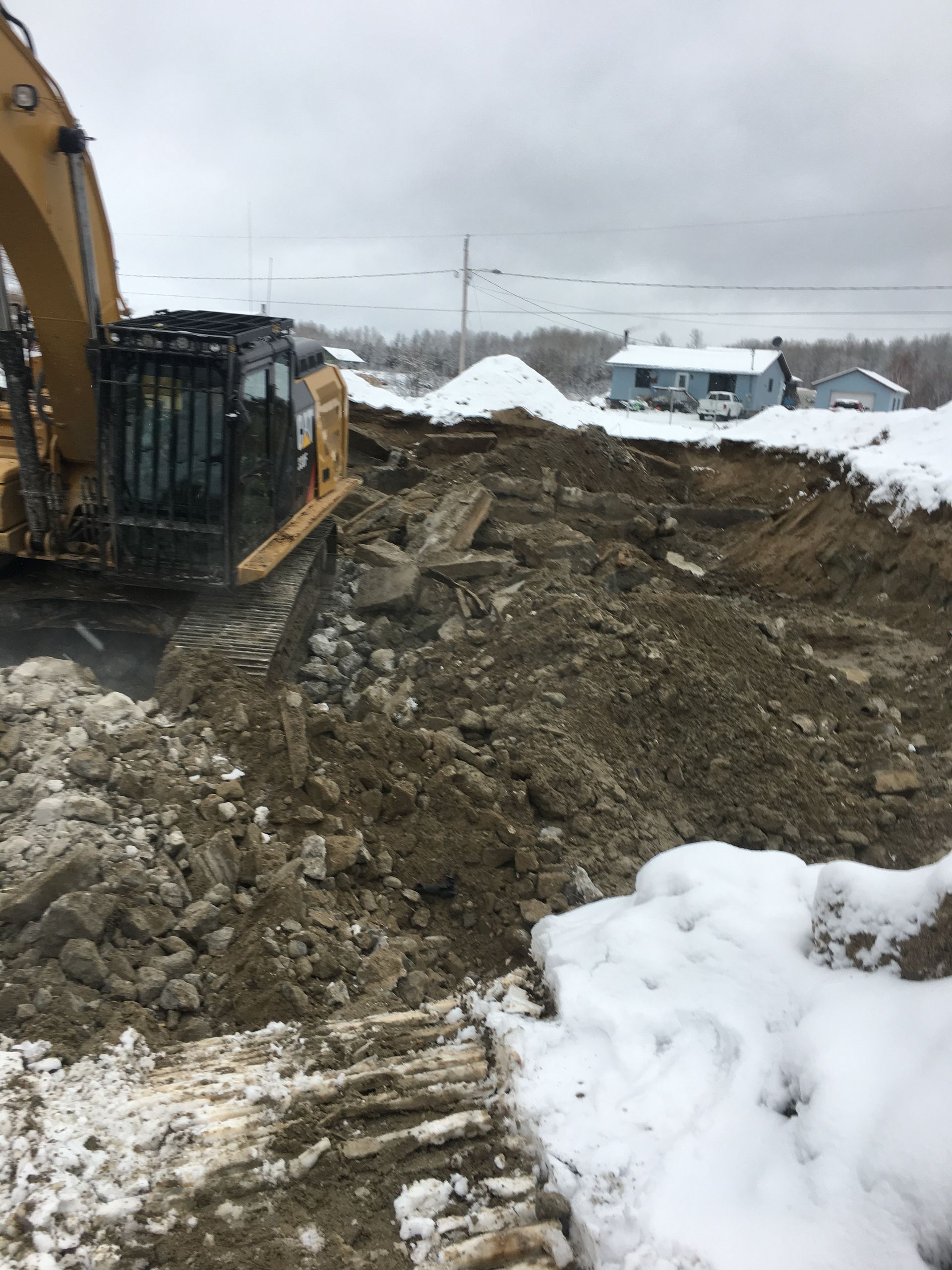 Une grosse pelle creuse un trou dans la neige.