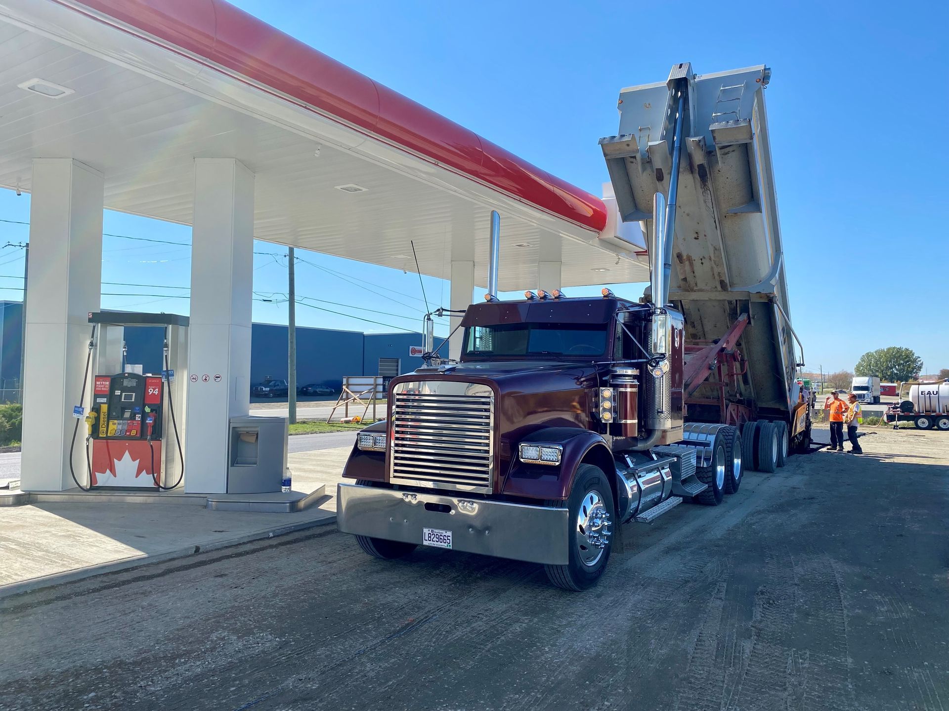 Un camion-benne est garé devant une station-service.