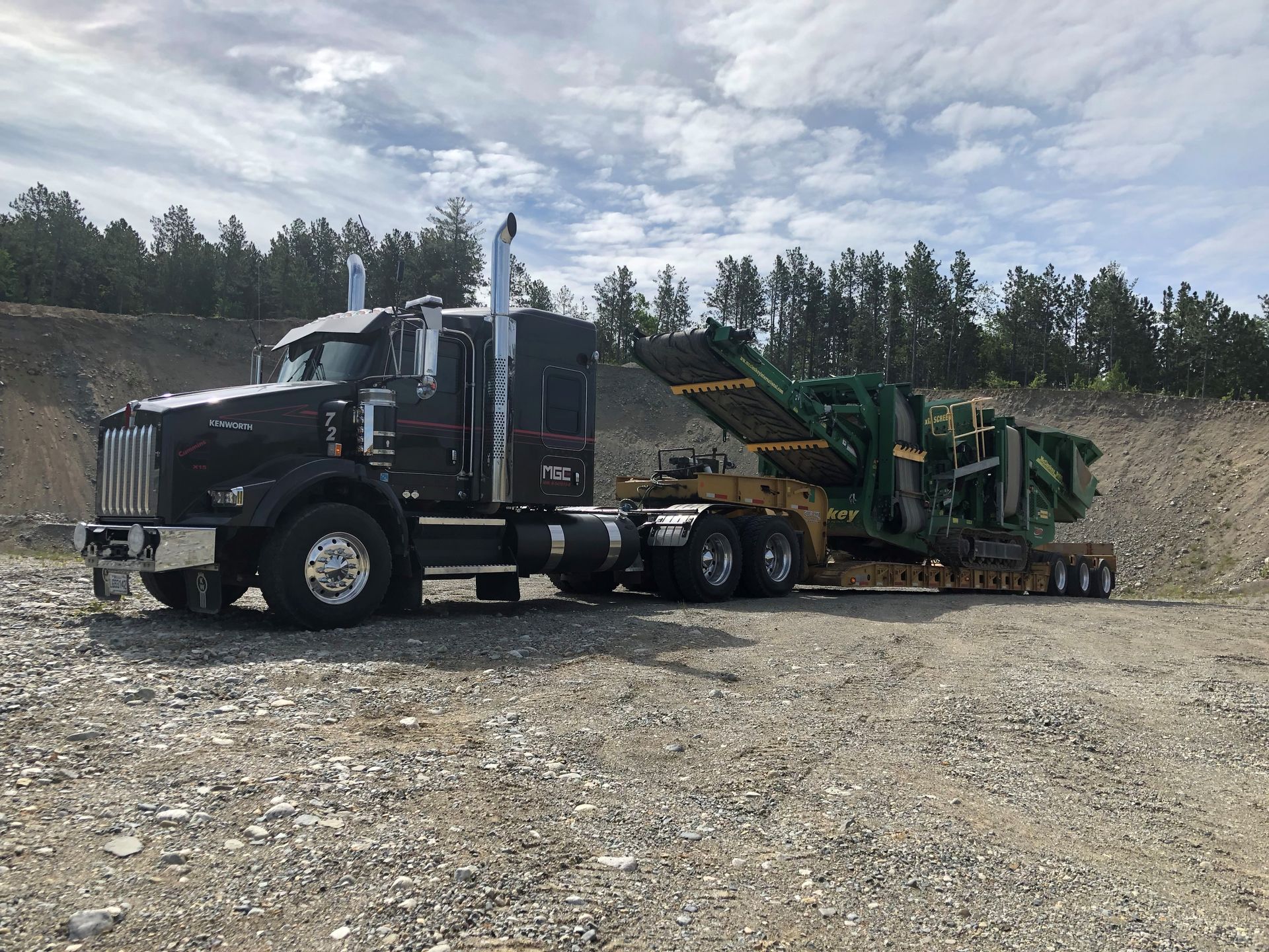 Un semi-remorque transporte une machine verte sur une remorque.